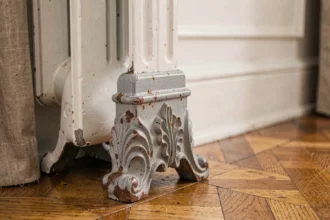 Pied de radiateur en fonte ancienne avec patine et rouille sur parquet en chêne