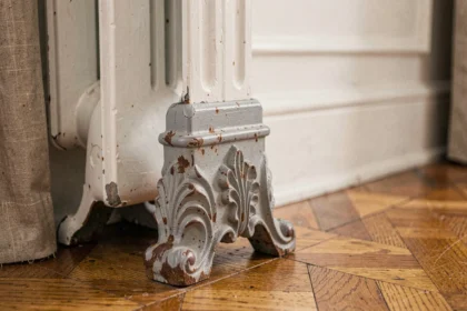 Pied de radiateur en fonte ancienne avec patine et rouille sur parquet en chêne